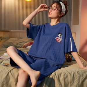 Marineblauwe katoenen nachtjapon met korte mouwen gedragen door een vrouw zittend op een bed in een huis