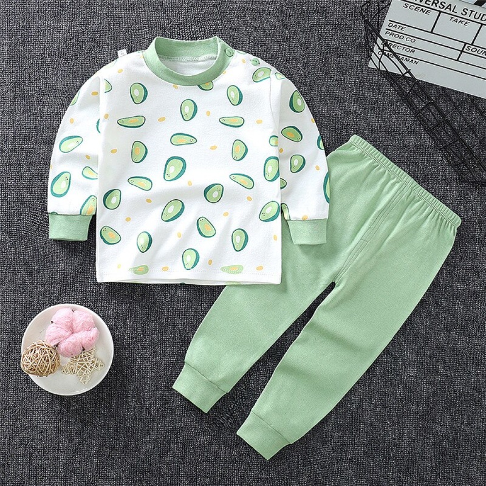 Pyjama van kleine jongen in avocadokatoen met effen groene broek modieus op een tapijt in een huis