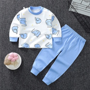 Pyjama van kleine jongen in olifantenkatoen met effen blauwe broek op een tapijt in een huis