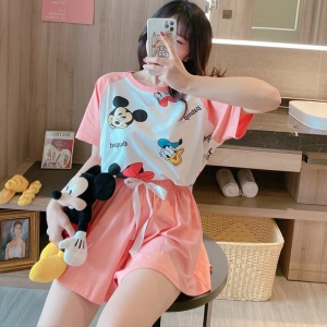 Roze zomerpyjama met opdruk van Mickey en Donald, gedragen door een vrouw die op een stoel zit en een phoo neemt in een huis