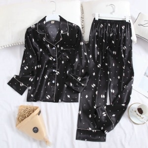 Tweedelige zwarte damespyjama met lange mouwen, gevouwen kraag en wit patroon op de riem