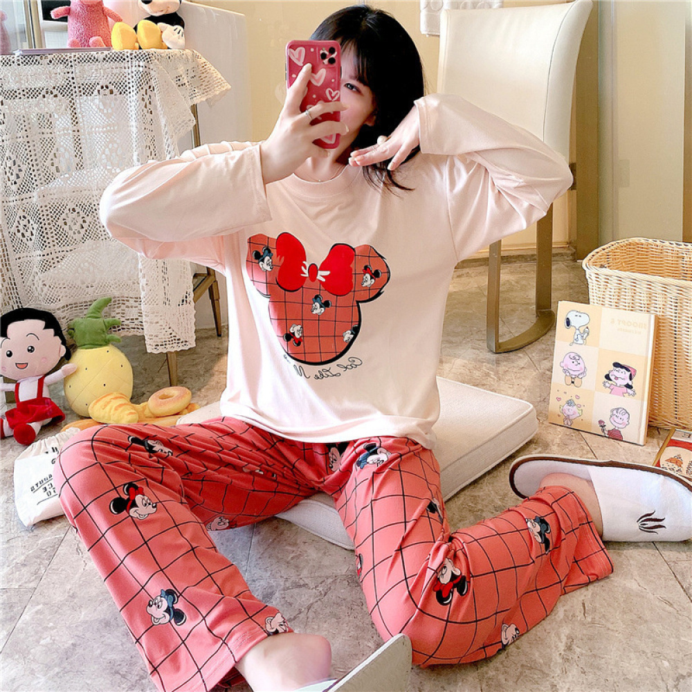 Tweedelige katoenen pyjama met lange mouwen en Minnie Mouse ontwerp met een meisje dat de pyjama draagt en een achtergrond van een kamer met opgezette dieren