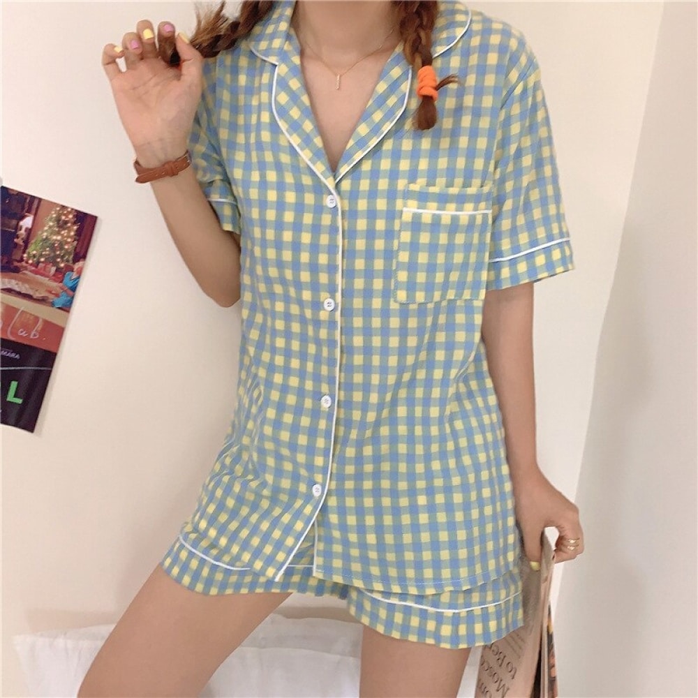 Blauw-geel geruite damespyjama met korte mouwen, gedragen door een vrouw in een huis