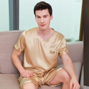 Gouden satijnen pyjama voor een man zittend op een bank in een huis