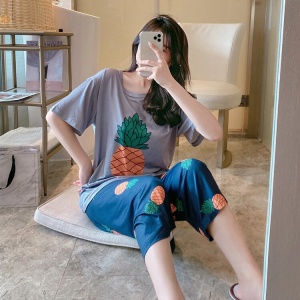 Tweedelige pyjama met ananasmotief gedragen door een vrouw zittend op een kussen voor een spiegel