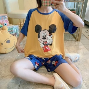 Tweedelig t-shirt en korte broek met Mickey-motief gedragen door een zittende vrouw die een foto neemt in een huis