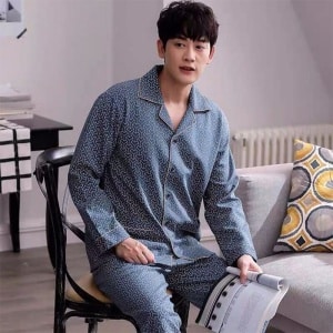 Modieuze katoenen pyjama gedragen door een man zittend op een stoel in een huis