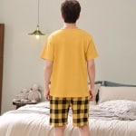 Garfield zomerpyjama met korte mouwen voor mannen in het geel gedragen door een man voor een bed in een huis