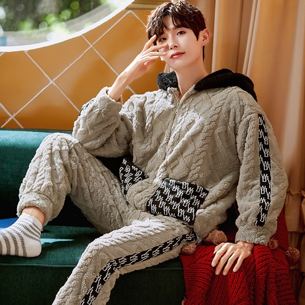 Warme herenpyjama met capuchon gedragen door een man zittend op een stoel in een huis