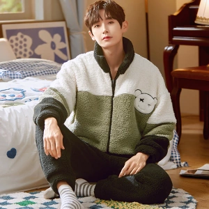 Winterpyjama met hoge kraag gedragen door een man zittend op een tapijt voor een bed in een huis