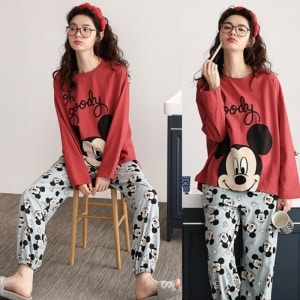 Mickey-pyjama voor vrouwen, gedragen door een vrouw met een hoofdband, zittend op een stoel in een huis