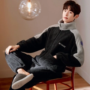 Zwarte winterpyjama voor mannen gedragen door een man zittend op een stoel in een huis