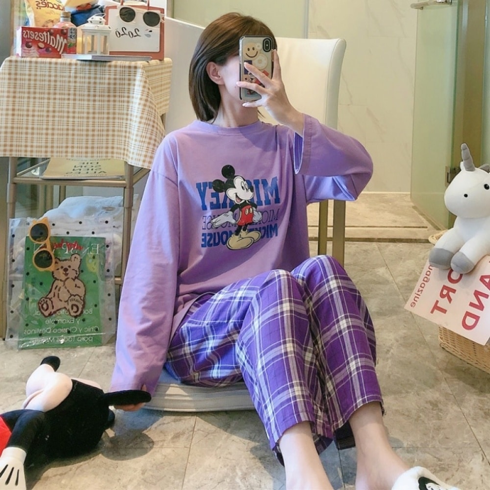 Mickey pyjama met paarse geruite broek gedragen door een vrouw die een foto neemt in een huis