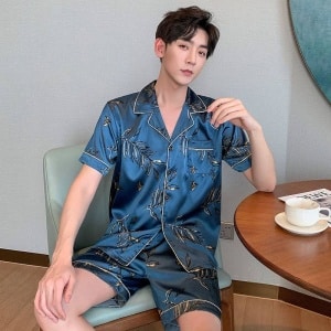 Blauwe zijden zomerpyjama voor mannen gedragen door een man zittend op een stoel in een huis