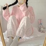 Zachte winterpyjama voor vrouwen in snoepjeskleur en roze-wit gestreepte broek, gedragen door een vrouw die een modieuze foto maakt