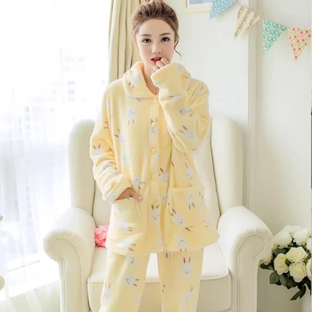 Winterpyjama met lange mouwen en een geel konijnenpatroon, zeer comfortabel, gedragen door een vrouw voor een stoel in een huis