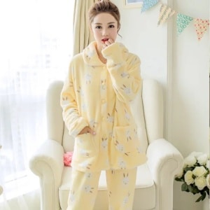 Winterpyjama met lange mouwen en een geel konijnenpatroon, zeer comfortabel, gedragen door een vrouw voor een stoel in een huis