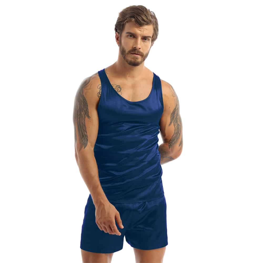 Donkerharige, getatoeëerde man draagt een zwarte satijnen herenpyjama bestaande uit een donkerblauw hemdje en een bijpassende donkerblauwe short