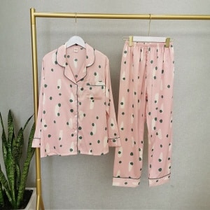 Tweedelige roze damespyjama met lange mouwen op een hanger in een huis