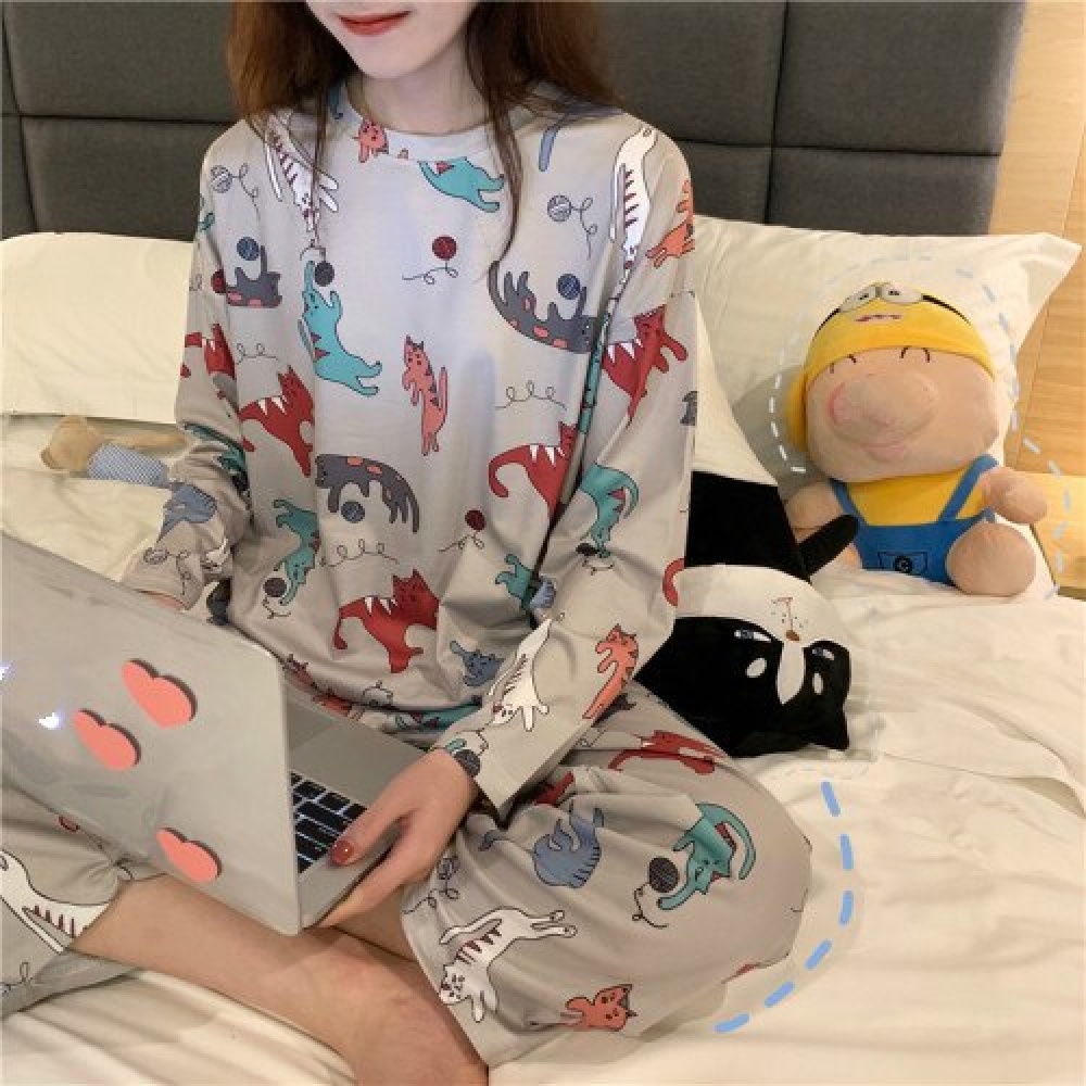 Kattenpyjama met lange mouwen gedragen door een vrouw zittend op een bed in een huis