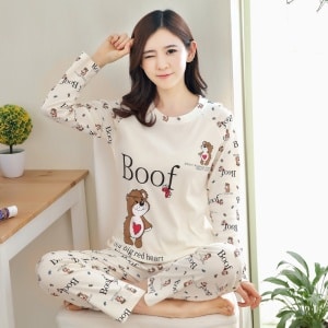 Witte herfstpyjama voor dames met Boof-patroon met een tafelachtergrond met een plant en een vrouw die de pyjama draagt