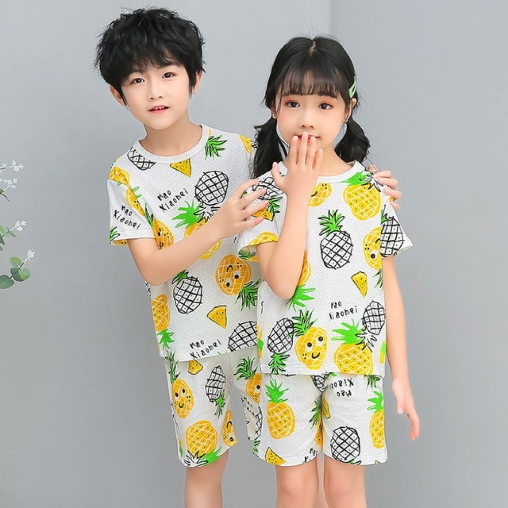 Witte tweedelige ananas pyjama met twee kinderen die de pyjama dragen en een grijze achtergrond