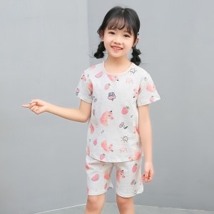Witte tweedelige pyjama met cartoonpatroon voor klein meisje met een klein meisje dat de pyjama draagt en een grijze achtergrond