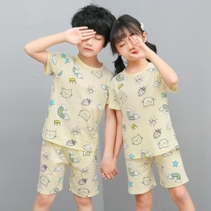 Witte tweedelige pyjama met cartoonmotief voor kinderen met twee kinderen die de pyjama dragen en een grijze achtergrond