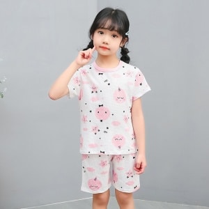 Witte tweedelige pyjama met cartoonprint voor kleine meisjes met een meisje dat de pyjama draagt