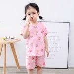 Roze tweedelige aardbeienpyjama voor kleine meisjes met een schattig meisje dat de pyjama draagt