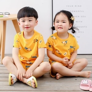 Gele tweedelige pyjama met cartoonmotief voor kinderen met twee kleine kinderen die de pyjama dragen