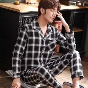 Geruite herenpyjama met lange mouwen en een man in de pyjama met keukenachtergrond