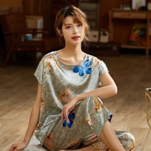 Tweedelige grijze zijden satijnen zomerpyjama met modieuze bloemenprint gedragen door een vrouw zittend op een tapijt in een huis