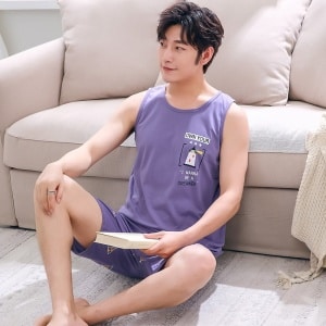 Paarse katoenen zomerpyjama zonder mouwen voor mannen gedragen door een man zittend op een tapijt voor een stoel in een huis