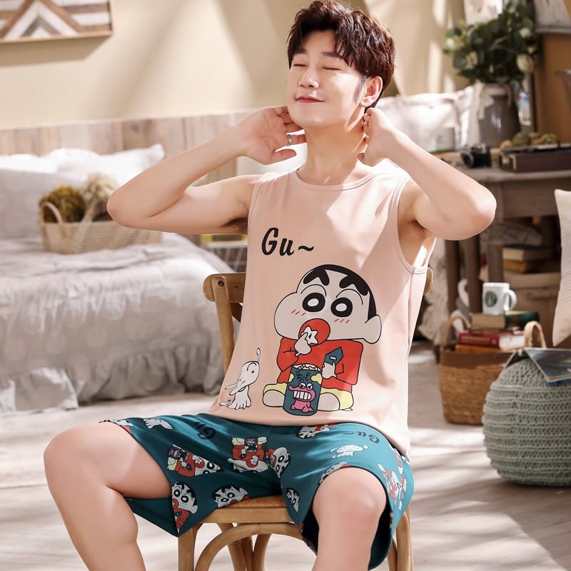 Mouwloze katoenen zomerpyjama met cartoonpatroon voor mannen gedragen door een man zittend op een stoel in een huis