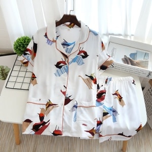 Witte zomerpyjama met korte mouwen en vogelprint voor vrouwen op een tafel met een tijdschrift als decoratie