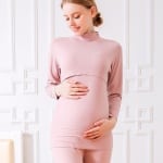 Roze katoenen tweedelige zwangerschapspyjama wordt gedragen door een zwangere blonde vrouw