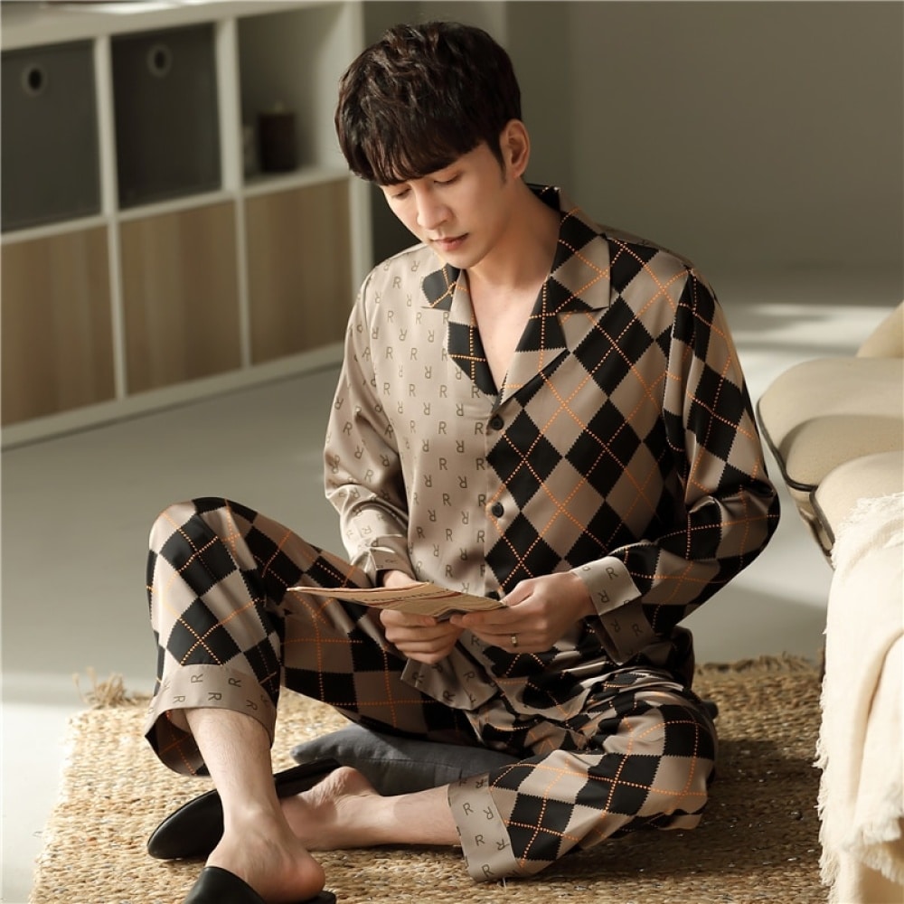 Katoenen herenpyjama met lange mouwen en omgeslagen kraag gedragen door een man zittend op een tapijt in een slaapkamer