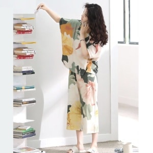 Zomerpyjama met vleermuismouw en bloemenprint gedragen door een vrouw met een boek in een huis