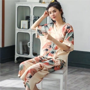 Tweedelige zomerpyjama met V-hals en bloemenpatroon gedragen door een vrouw zittend op een stoel in een huis