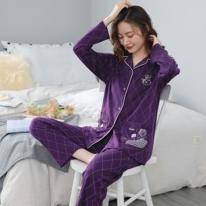 Paarse tweedelige damespyjama met geometrische patronen een vrouw die de paarse pyjama draagt, met op de achtergrond een slaapkamer