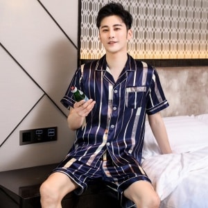 Luxe herenpyjama met korte mouwen en omgeslagen kraag met een man die de pyjama draagt met een slaapkamerachtergrond