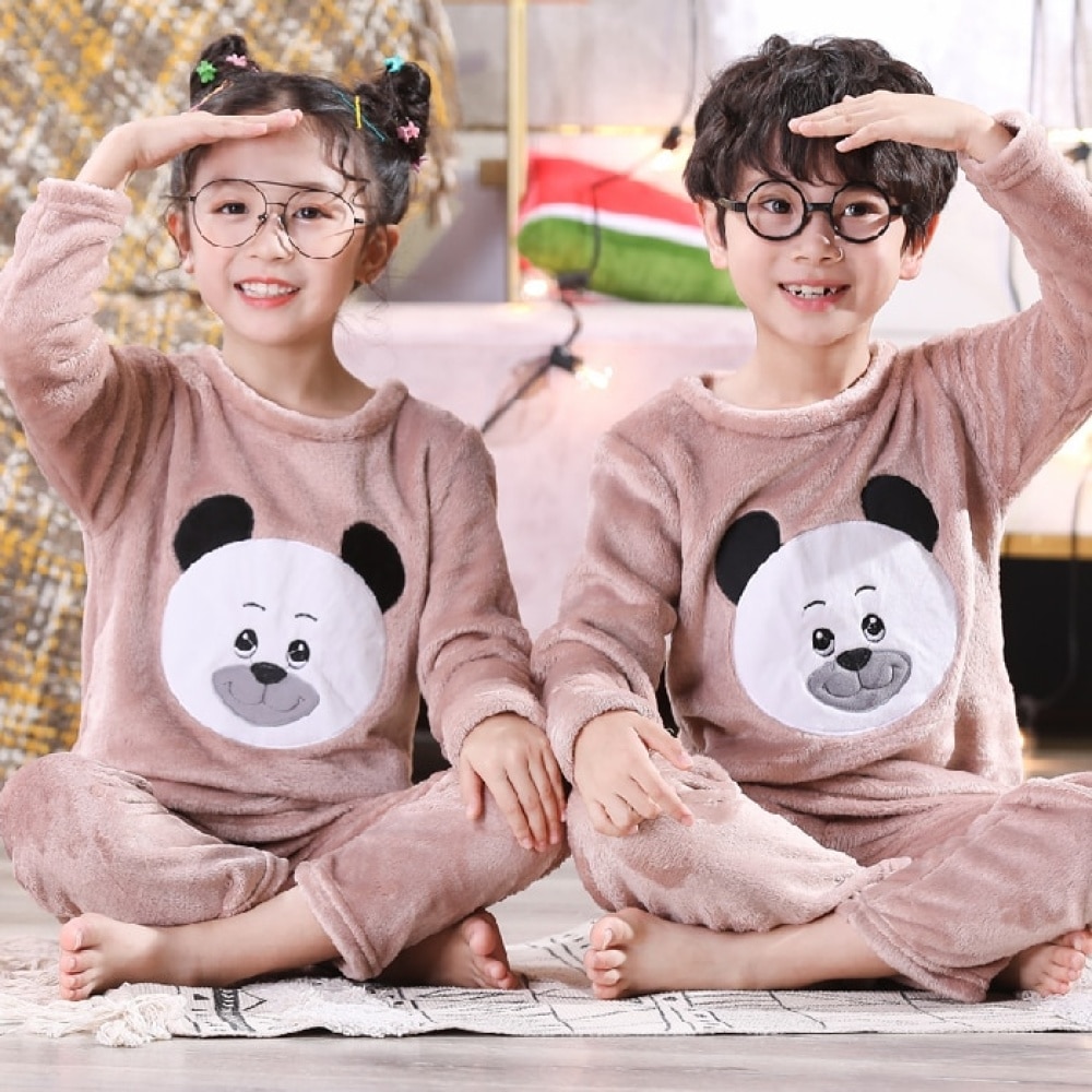 Flanellen pyjama met lange mouwen en panda print voor kinderen gedragen door een kleine jongen en een klein meisje zittend op een tapijt in een huis