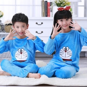 Blauwe flanellen pyjama met lange mouwen en Doraemon print voor kind zittend op een tapijt in een huis