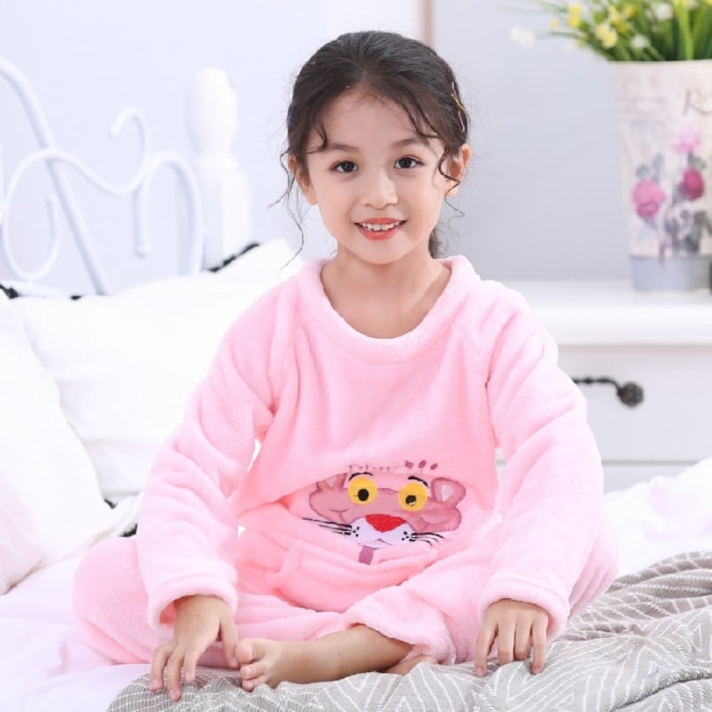 Flanellen pyjama met roze panterprint voor een klein meisje gedragen op een bed in een huis