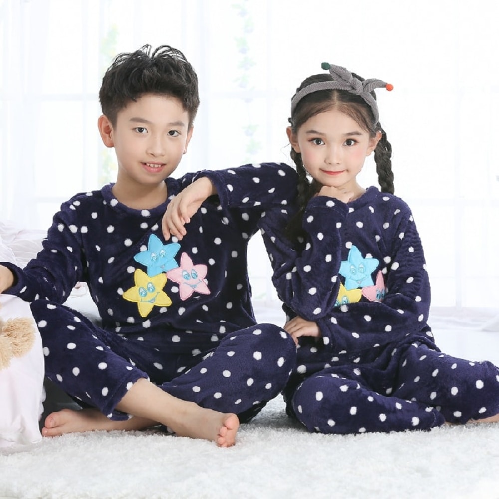 Meisjespyjama van flanel met lange mouwen en zeemeerminnenmotief gedragen door een klein meisje en een kleine jongen zittend op een tapijt