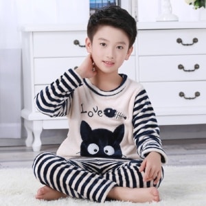 Tweedelige zwart-wit gestreepte flanellen pyjama gedragen door een jongen zittend op een tapijt in een huis