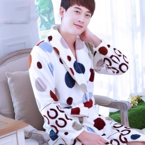 Herenpyjama in flanel met veelkleurig stippenpatroon gedragen door een man zittend op een stoel in een huis