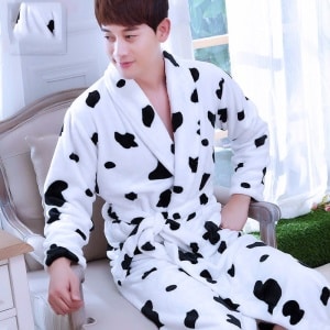 Modieuze mannen kimono pyjama met koeienprint, gedragen door een man die op een stoel zit