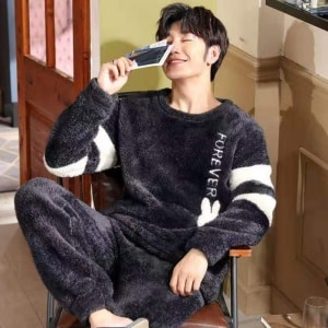 Warme fleece pyjama voor heren gedragen door een man zittend op een stoel in een modieus huis